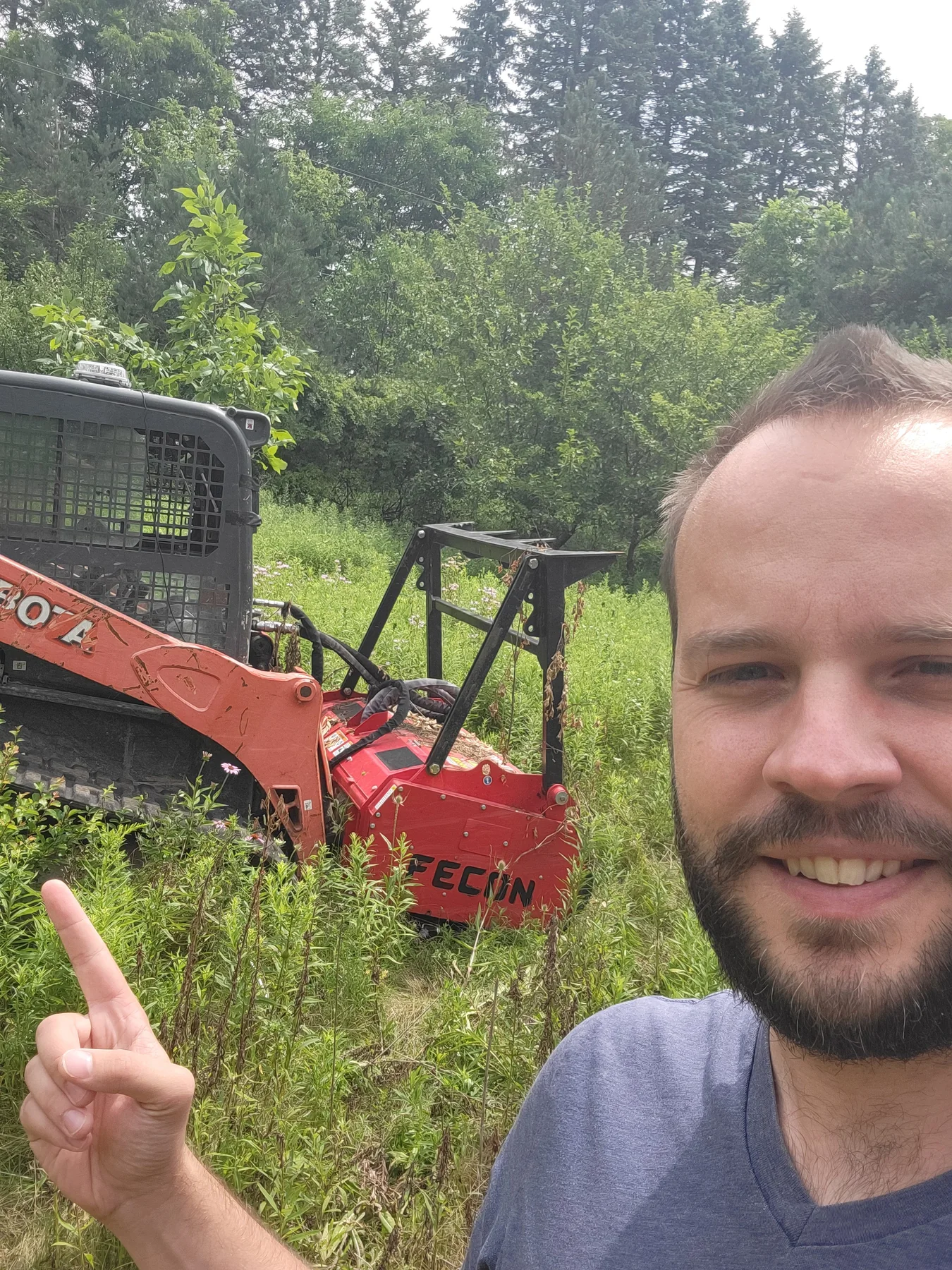 Alex Craig beside land-clearing equipment on a Dimondale property