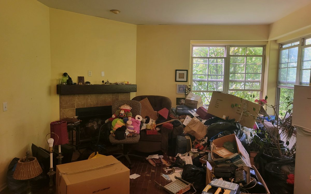 Lansing hoarder house living room with contents left behind before an as-is cleanout sale